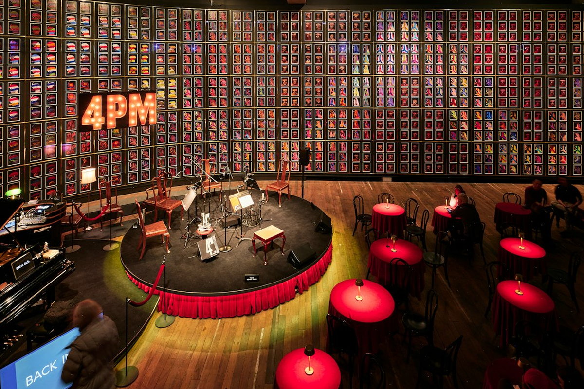 Formally dressed adult guests around a themed table in a hall lit from above